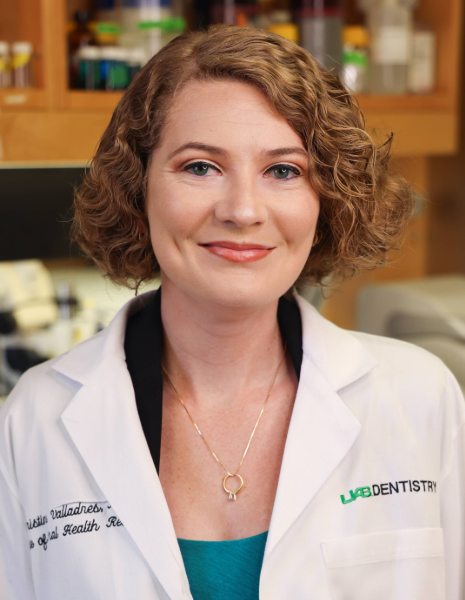 Woman with short dirty blonde hair wearing a white coat smiling in a lab setting